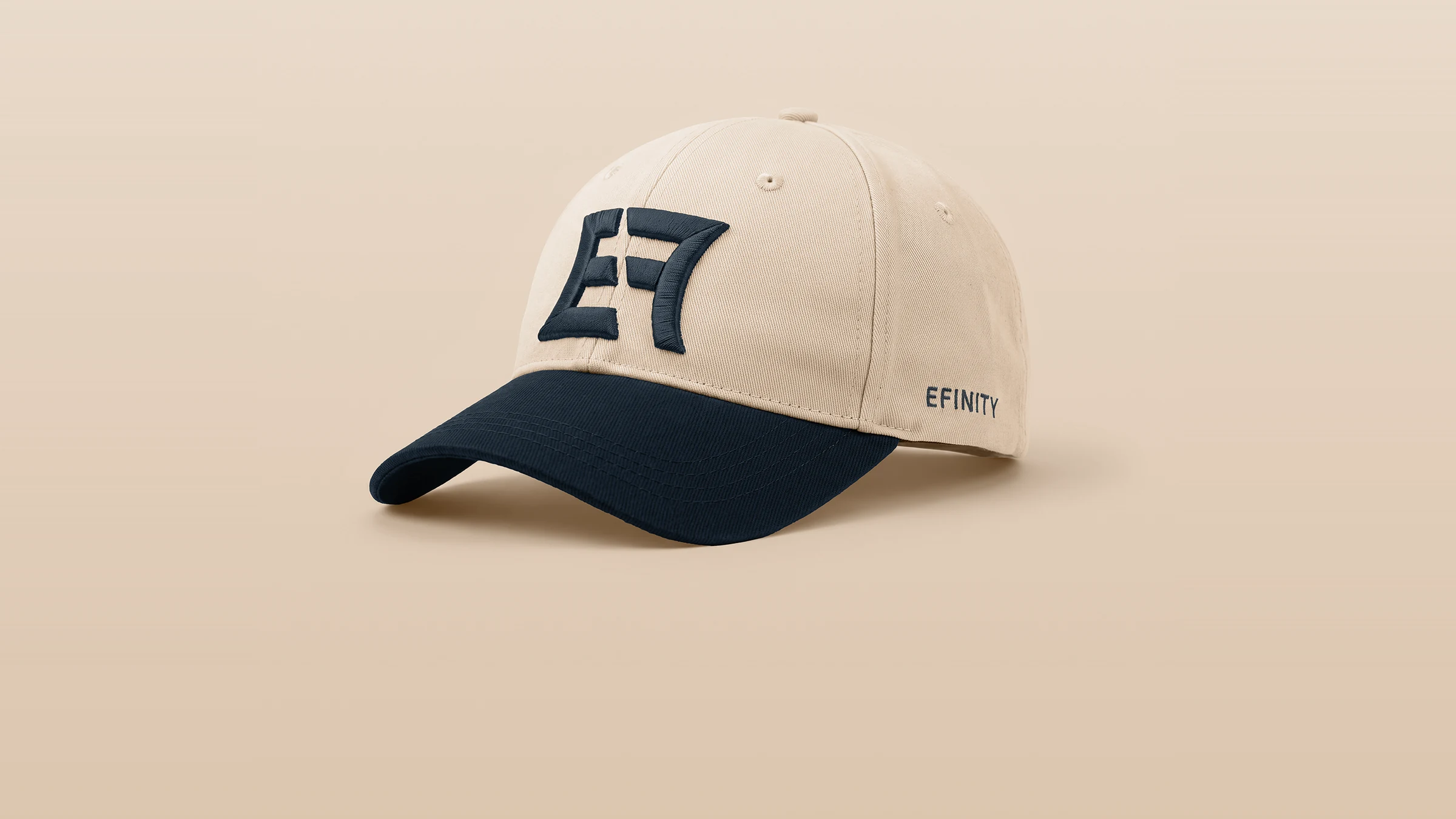 EFINITY cap in off-white cotton twill with a dark navy bill, seen at a three-quarter angle, the EF monogram embroidered on the crown and EFINITY on the side